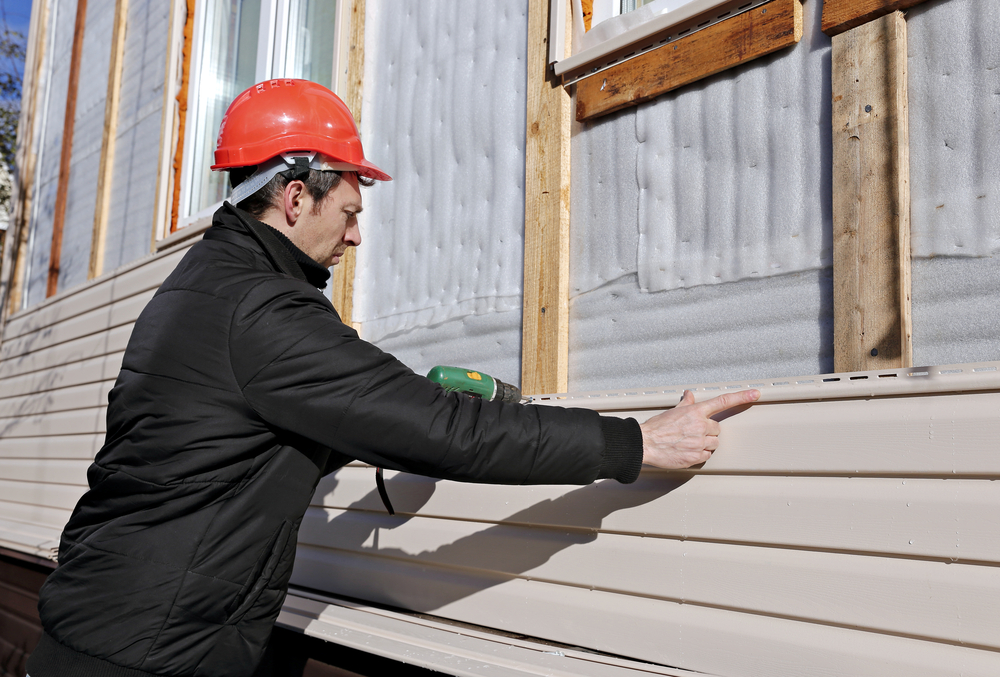 Contractor installing vinyl siding on a Ridgewood home